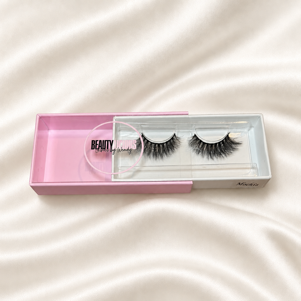Mochi's faux lashes in pink packaging on soft ivory satin