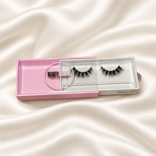 Fancy Face faux lashes in pink packaging on soft ivory satin