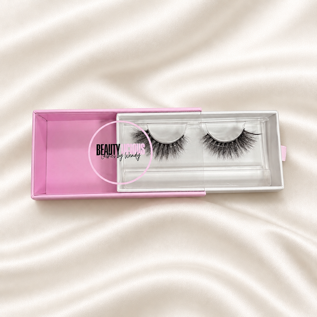 Baby Doll lashes in pink packaging on a soft ivory satin background