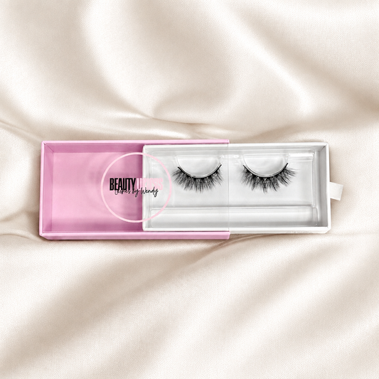 Dolly faux lashes in pink packaging on soft ivory satin