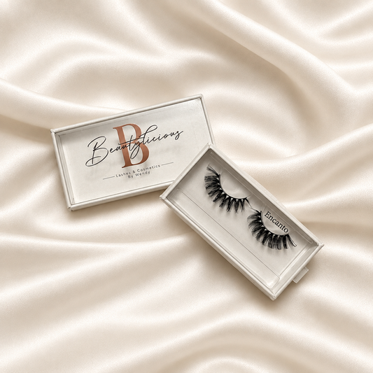 Encanto faux lashes in silver-white packaging on soft ivory satin
